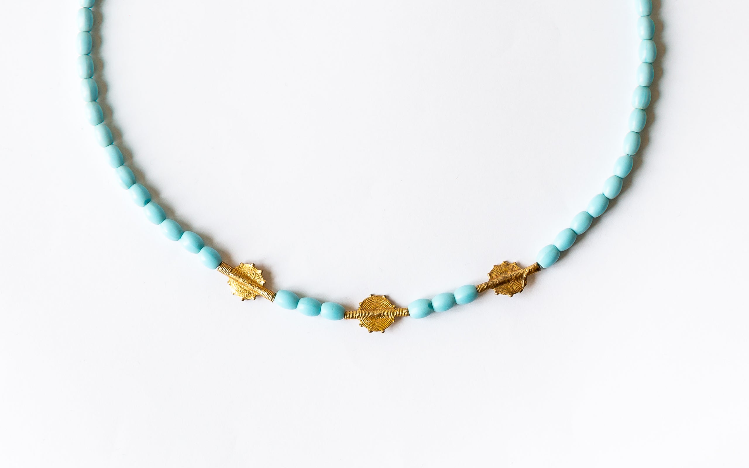 Halskettendetail der Perlen in Türkisfarbe und goldene Scheibenperlen.