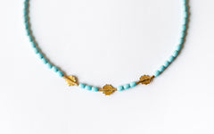 Halskettendetail der Perlen in Türkisfarbe und goldene Scheibenperlen.