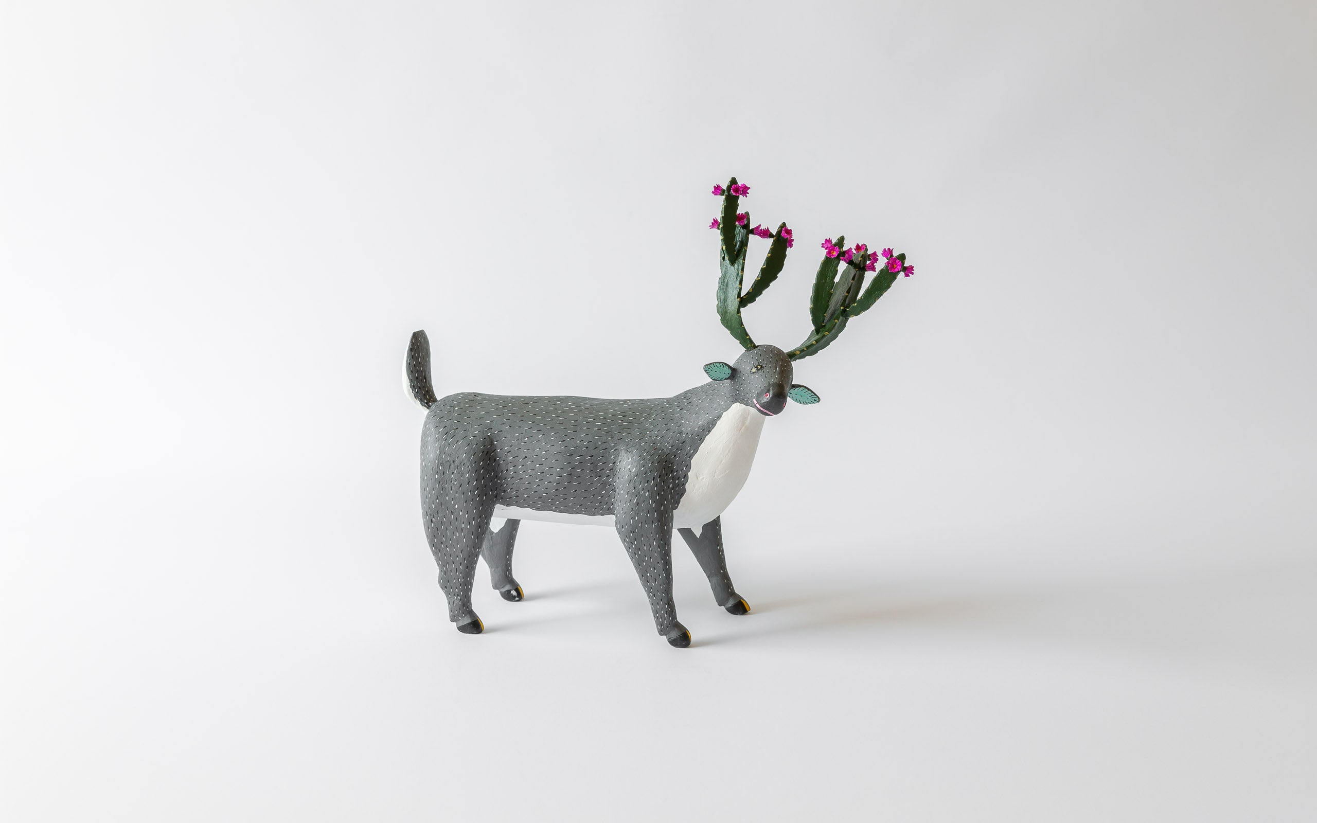 Ein Hirsch mit einem Geweih aus Kaktus mit lila Blüten, graues Fell