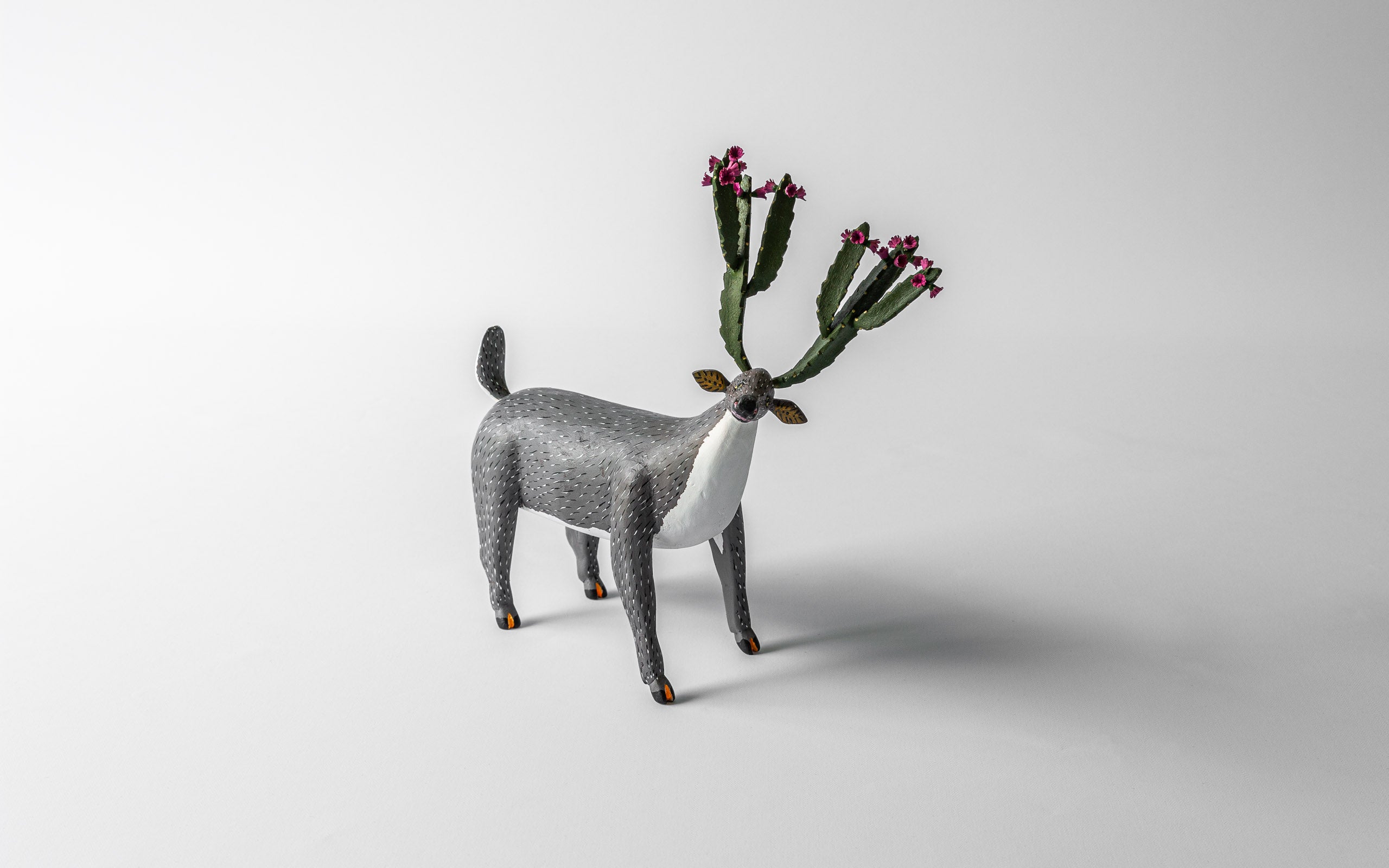 Hirsch mit Kaktus-Geweih, das Geweih hat rosa Blüten, der Hirsch ist grau, Kunsthandwerk aus Oaxaca.