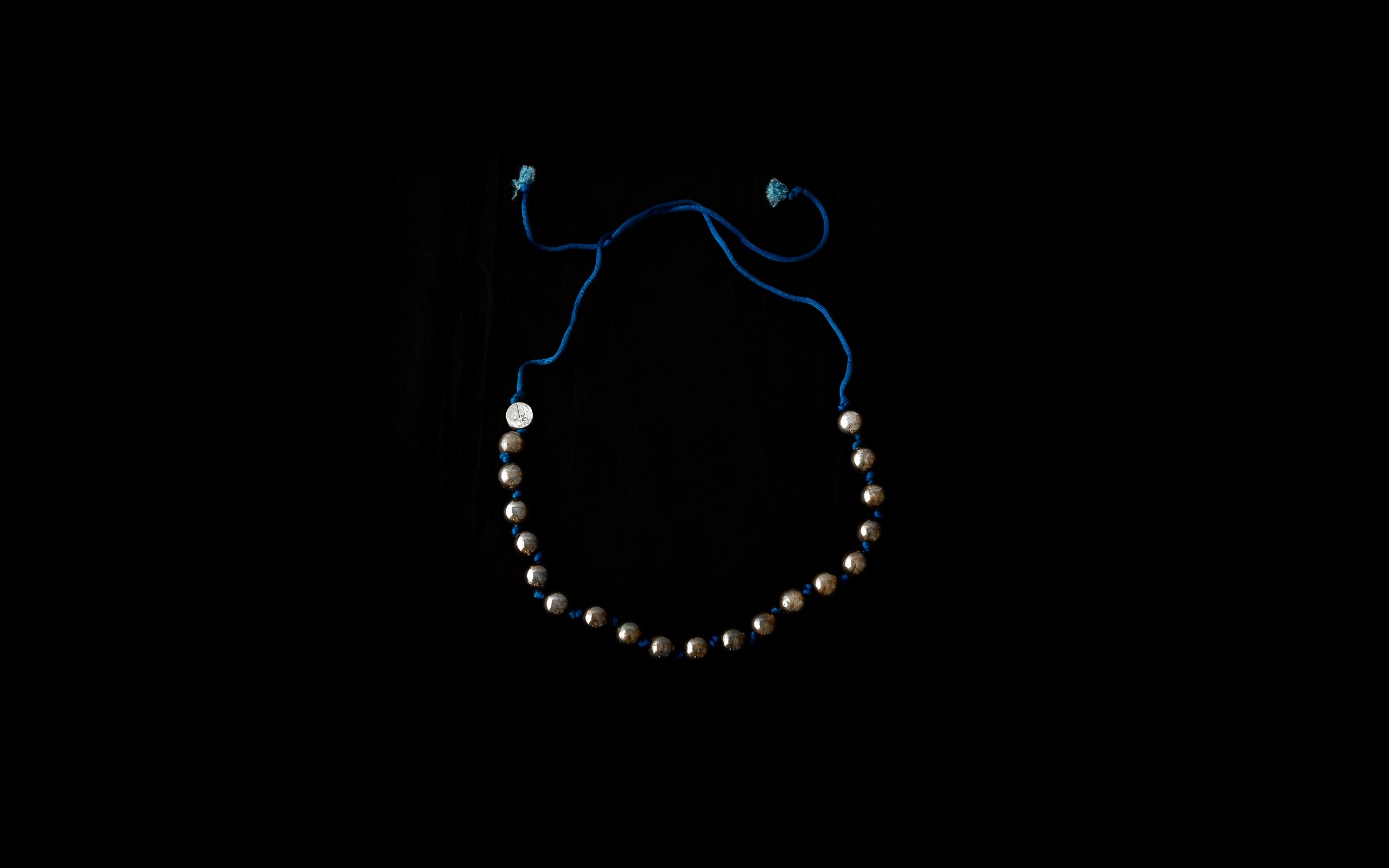 Halskette mit Silberkugeln auf blauer Seidenkordel..