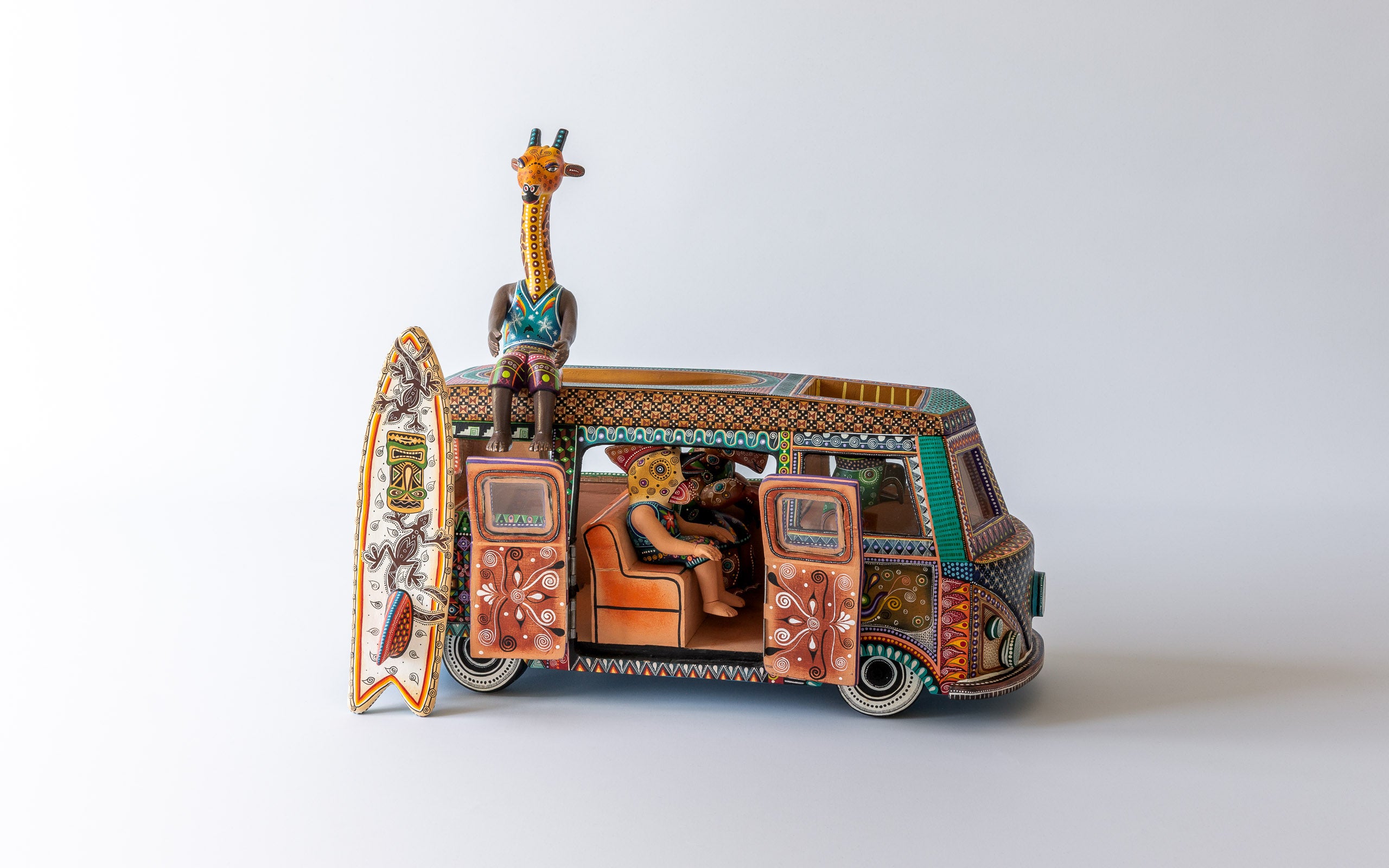 VW Kombi Surfen: Andere Seite des VW Kombi mit offenen Türen, Giraffe auf Dach sitzend, Surfboard bereit.